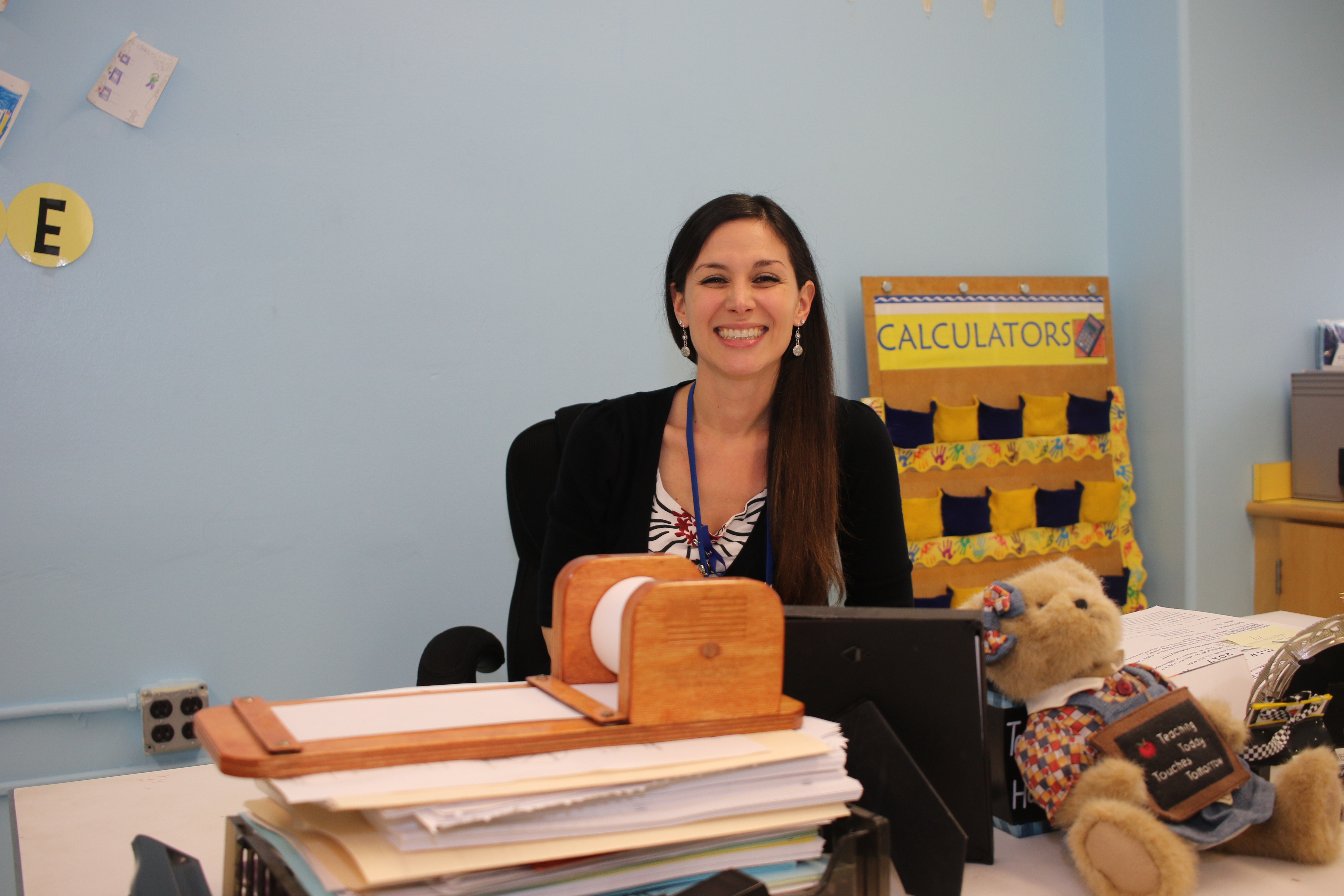 teacher with long hair sits at desk 